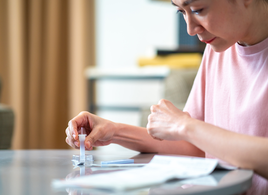 Woman using a self-test kit at home, illustrating the concept of direct-to-consumer (DTC) genetic testing.