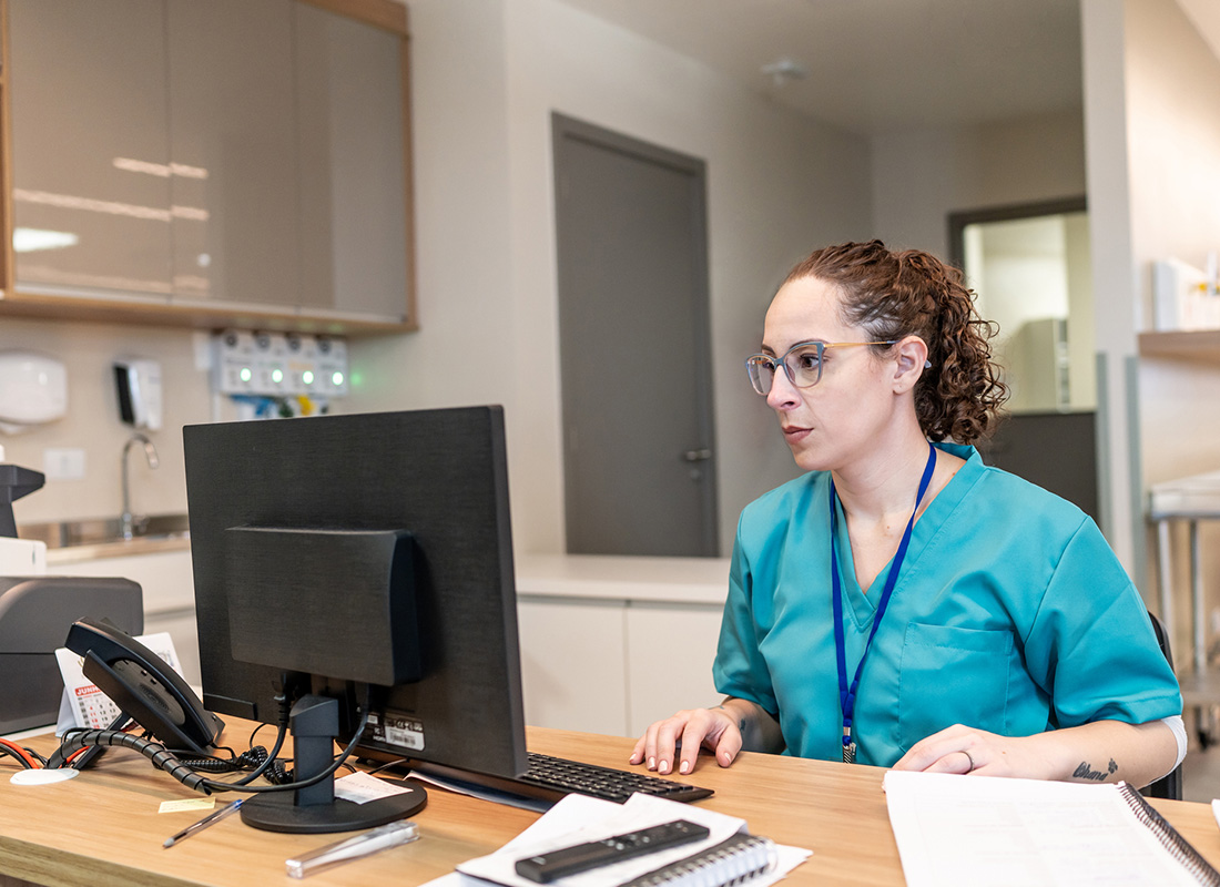 A healthcare professional sits at a computer in a medical office, illustrating billing for genetic testing.