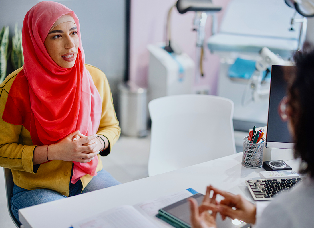 A female patient in a hijab meets with her female doctor.