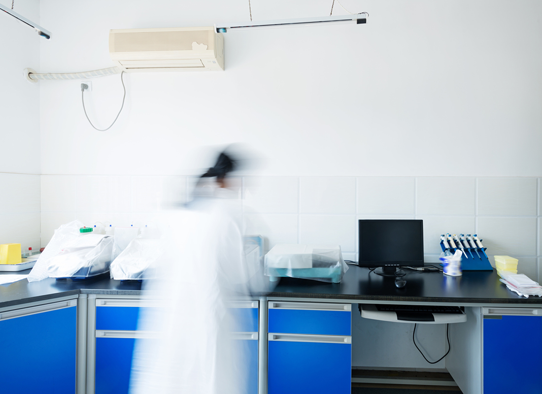 A laboratory professional works in a chemistry laboratory. They are blurred to demonstrate speed.