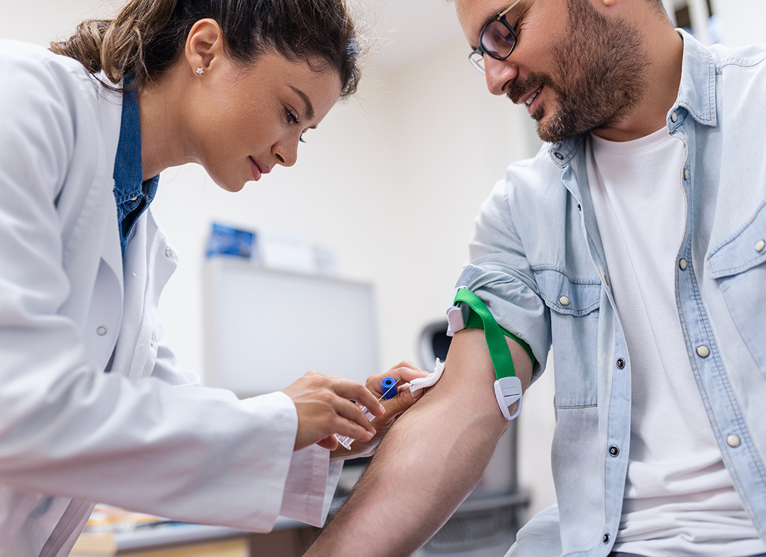 Middle-aged man prepares to get a blood test from a healthcare professional.