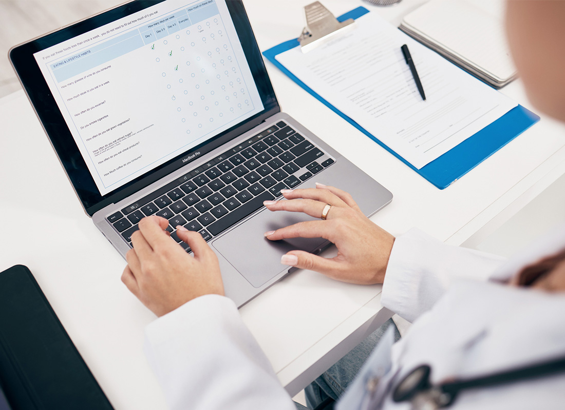 A closeup of a female doctor typing on a laptop with a checklist on the screen, illustrating the concept of ordering laboratory tests.