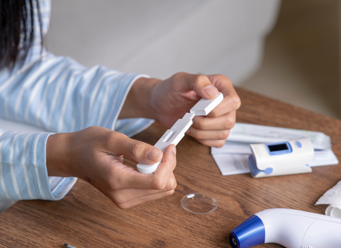 A person with long black hair wearing a blue-and-white striped shirt uses an at-home testing kit for infectious disease diagnostics.