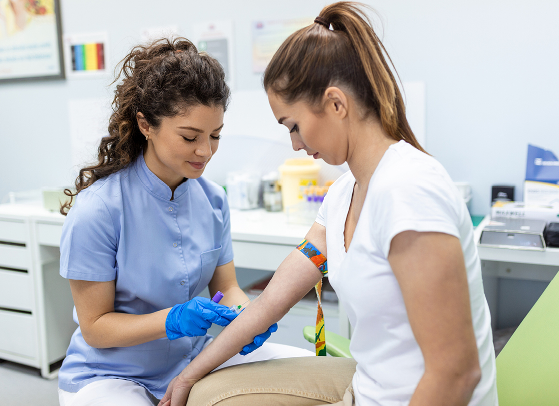 A female medical professional prepares a female patient for a blood test.