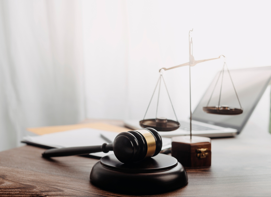 A judge’s gavel, scales, laptop, folder, and documents sit on a desk, illustrating a business law concept.